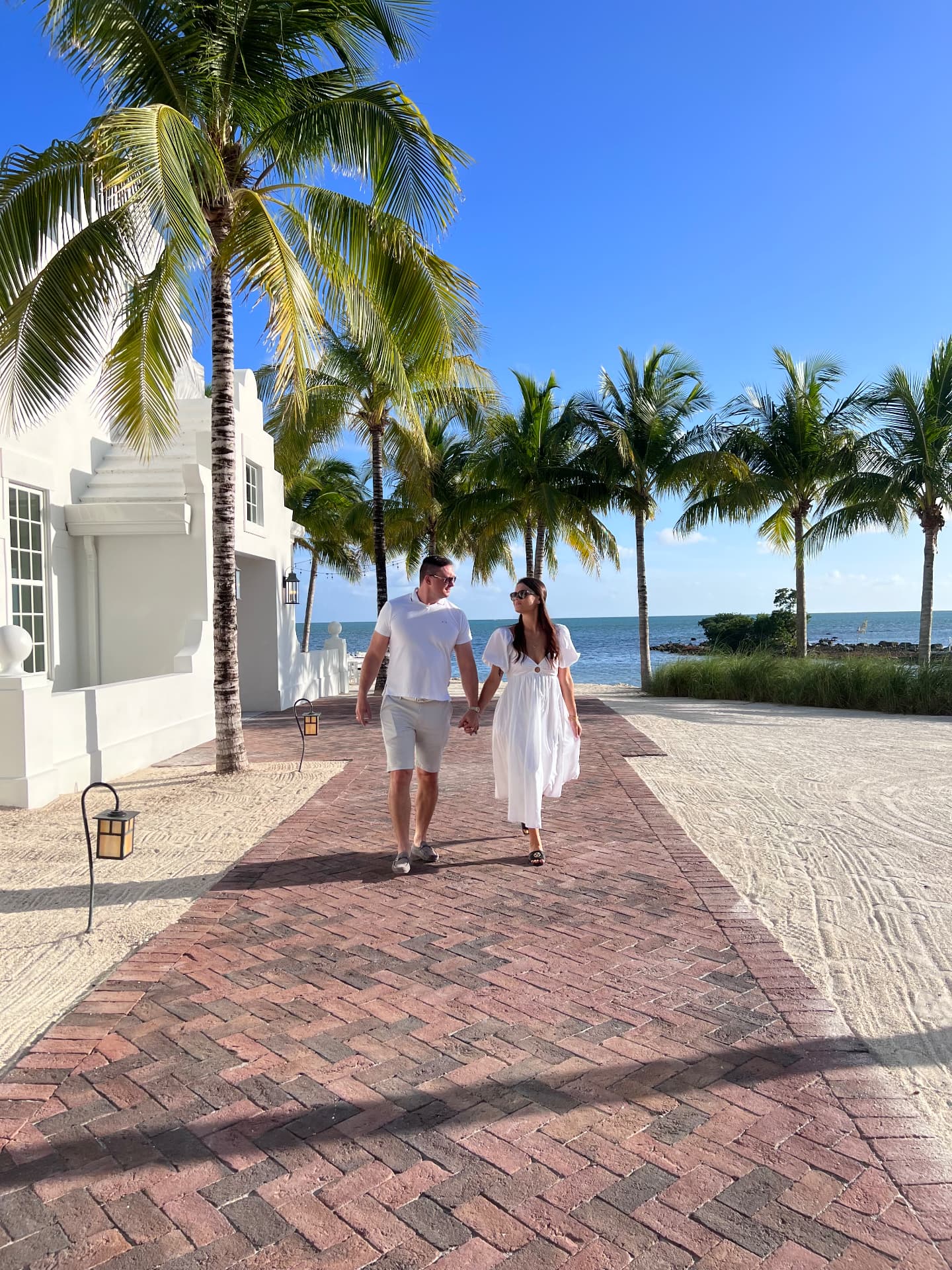Roman and Daryna Sviridenko, owners of Sunshine Keys Vacation, walking along a palm-lined waterfront path in the Florida Keys